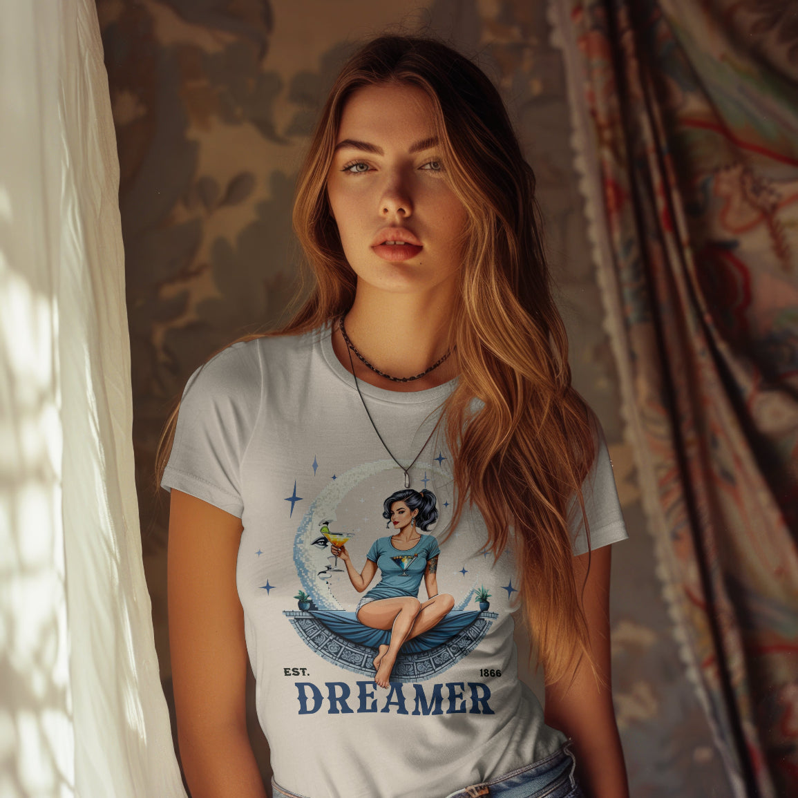 Woman wearing a t-shirt with a graphic design and the word 'Dreamer' in a room with curtains.