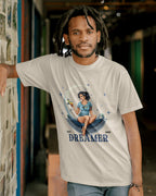 A person wearing a beige triblend T-shirt with a graphic design.