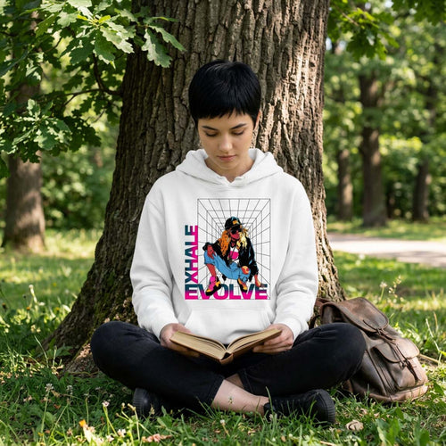 young woman sitting under a tree reading, wearing a white hoodie with a evolve, exhale graphic.