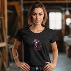 A woman wearing a black short-sleeve t-shirt with a graphic design in the center, standing in a room with wooden background.