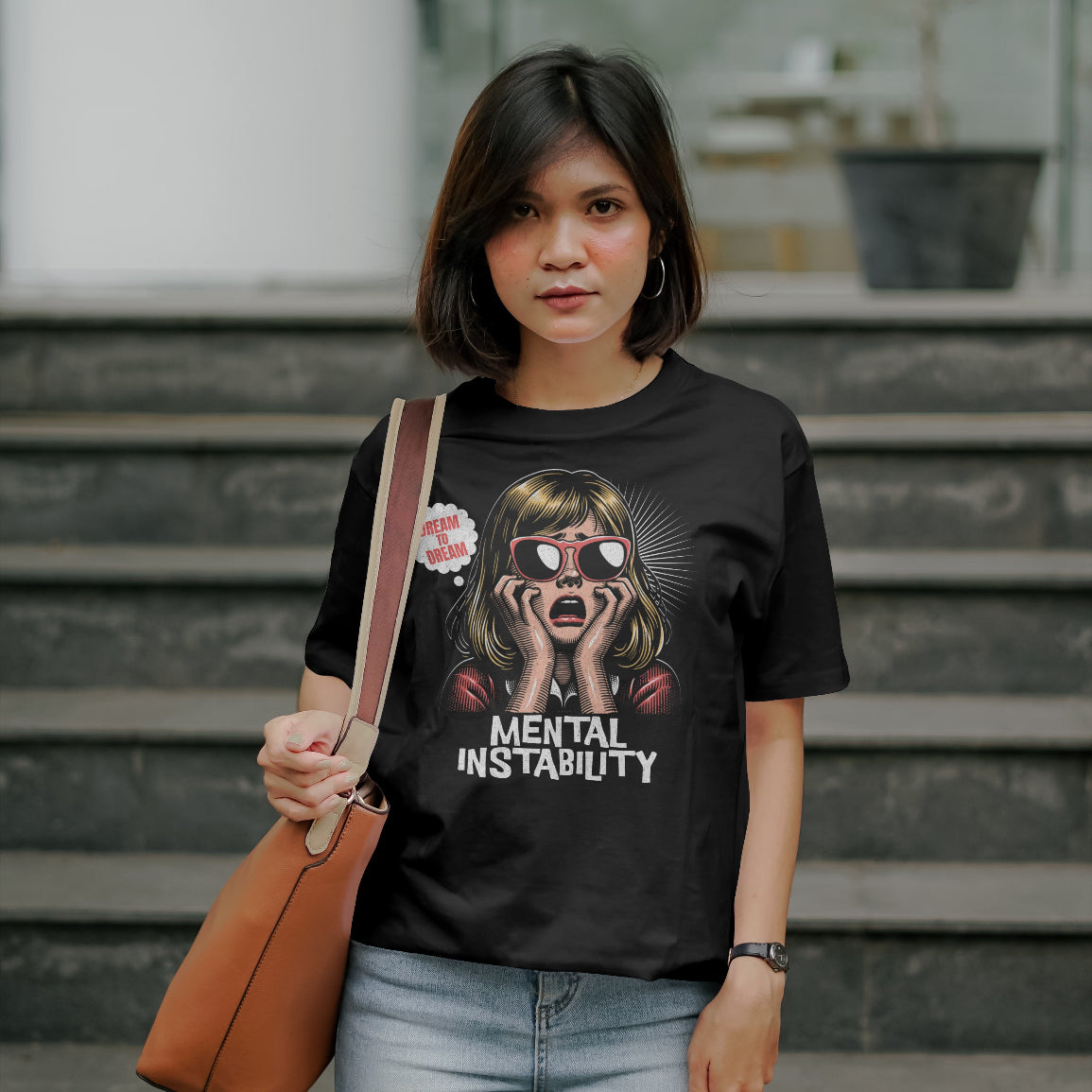Woman wearing a black t-shirt with a Mental Instability graphic design and text, standing outdoors.