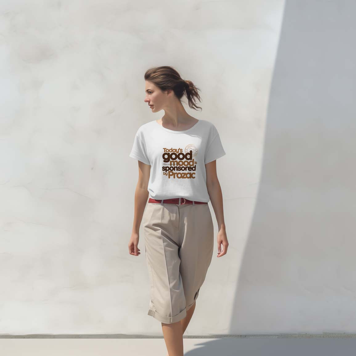 Woman wearing a white t-shirt with text standing against a plain wall.