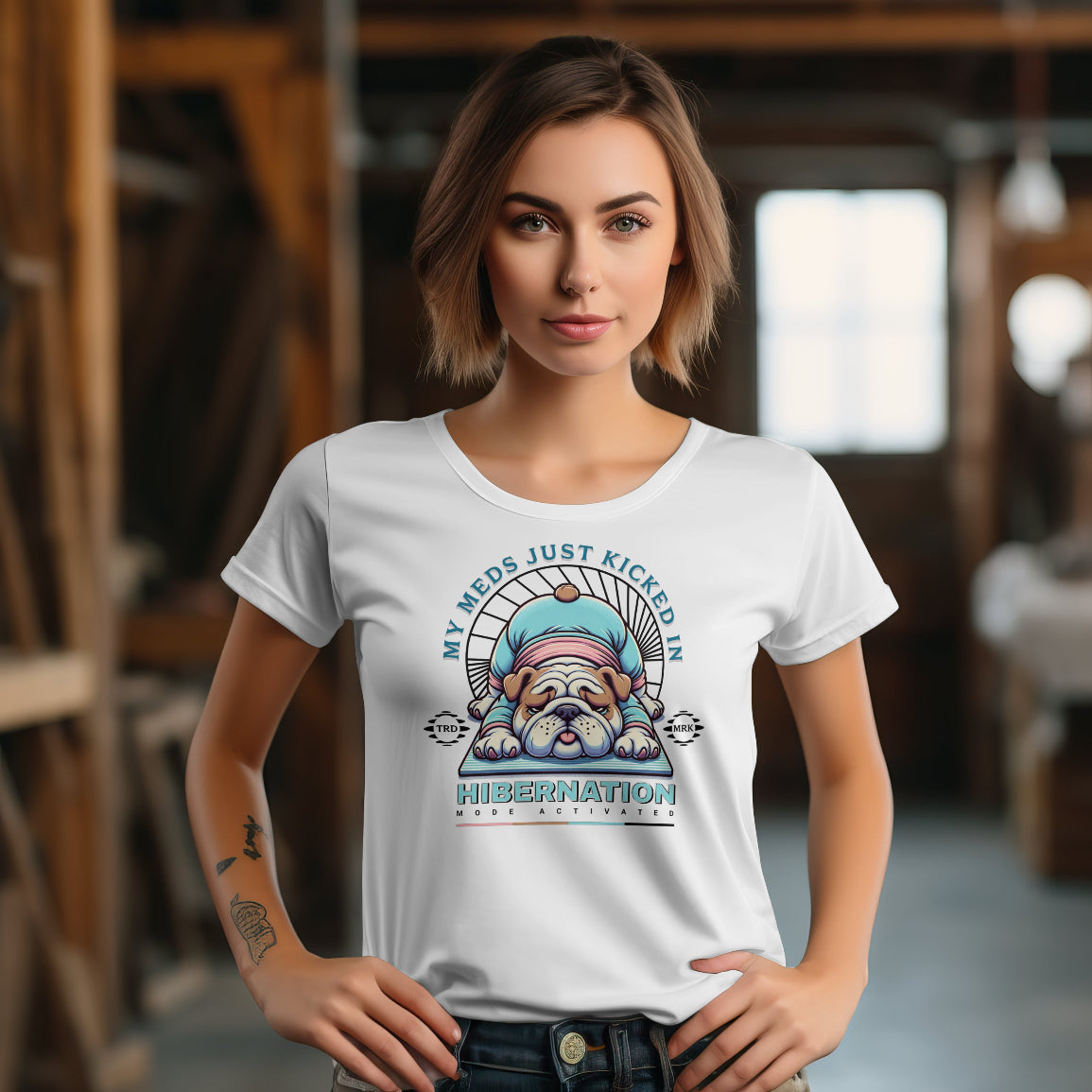Woman wearing a white t-shirt with a graphic design of a dog in hibernation, text 'My meds just kicked in hibernation', in an indoor setting.