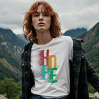 Person wearing a white t-shirt with colorful design in a mountainous landscape