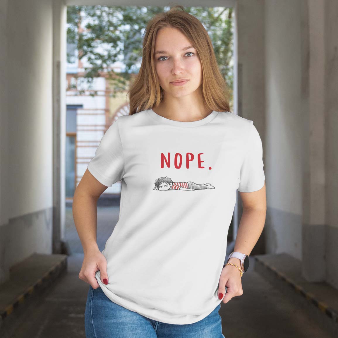 Woman wearing a white t-shirt with 'NOPE.' text and character graphic, standing indoors.