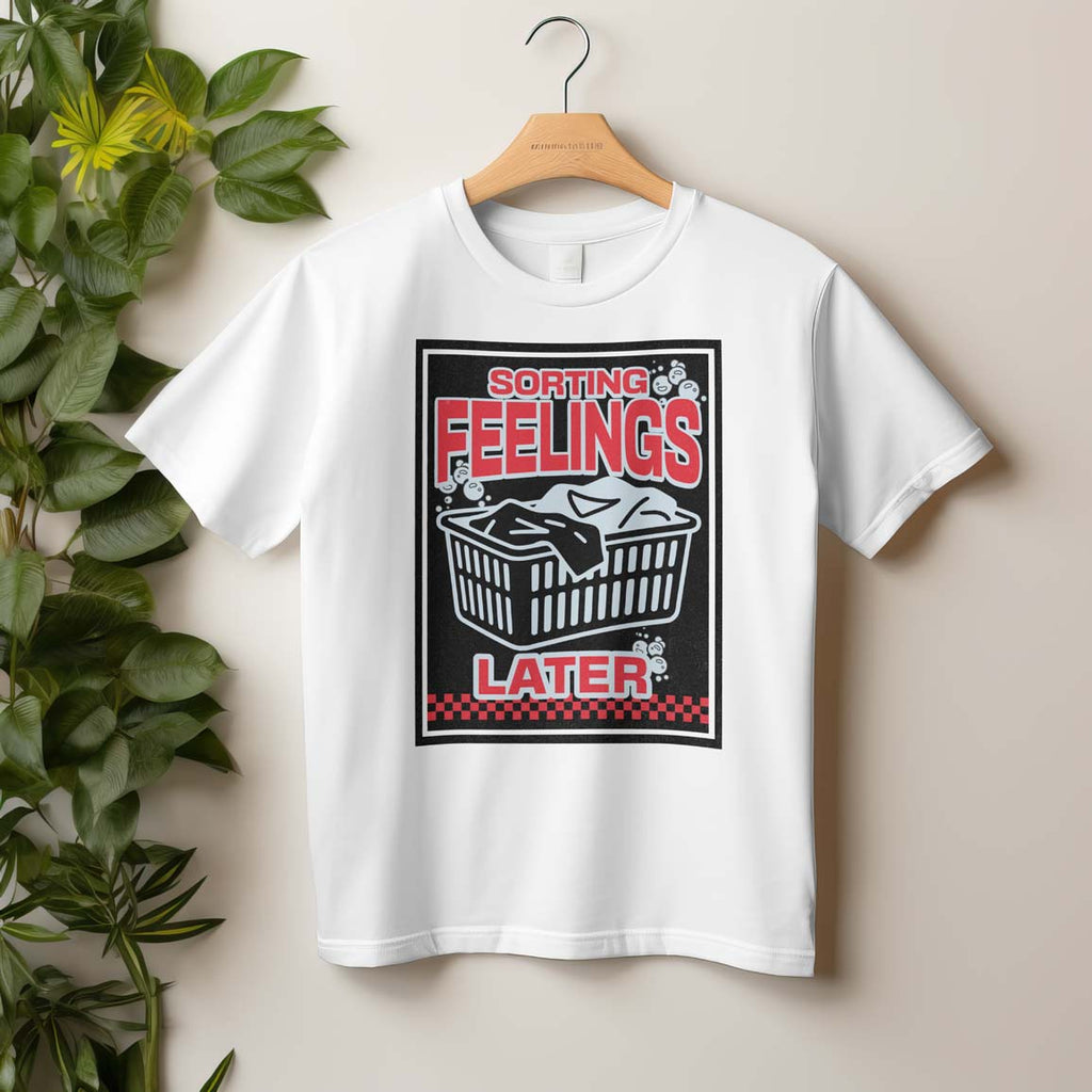 White t-shirt with graphic design on a hanger against a beige wall.