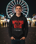 Person wearing a black hoodie with red text in front of a Ferris wheel at night.