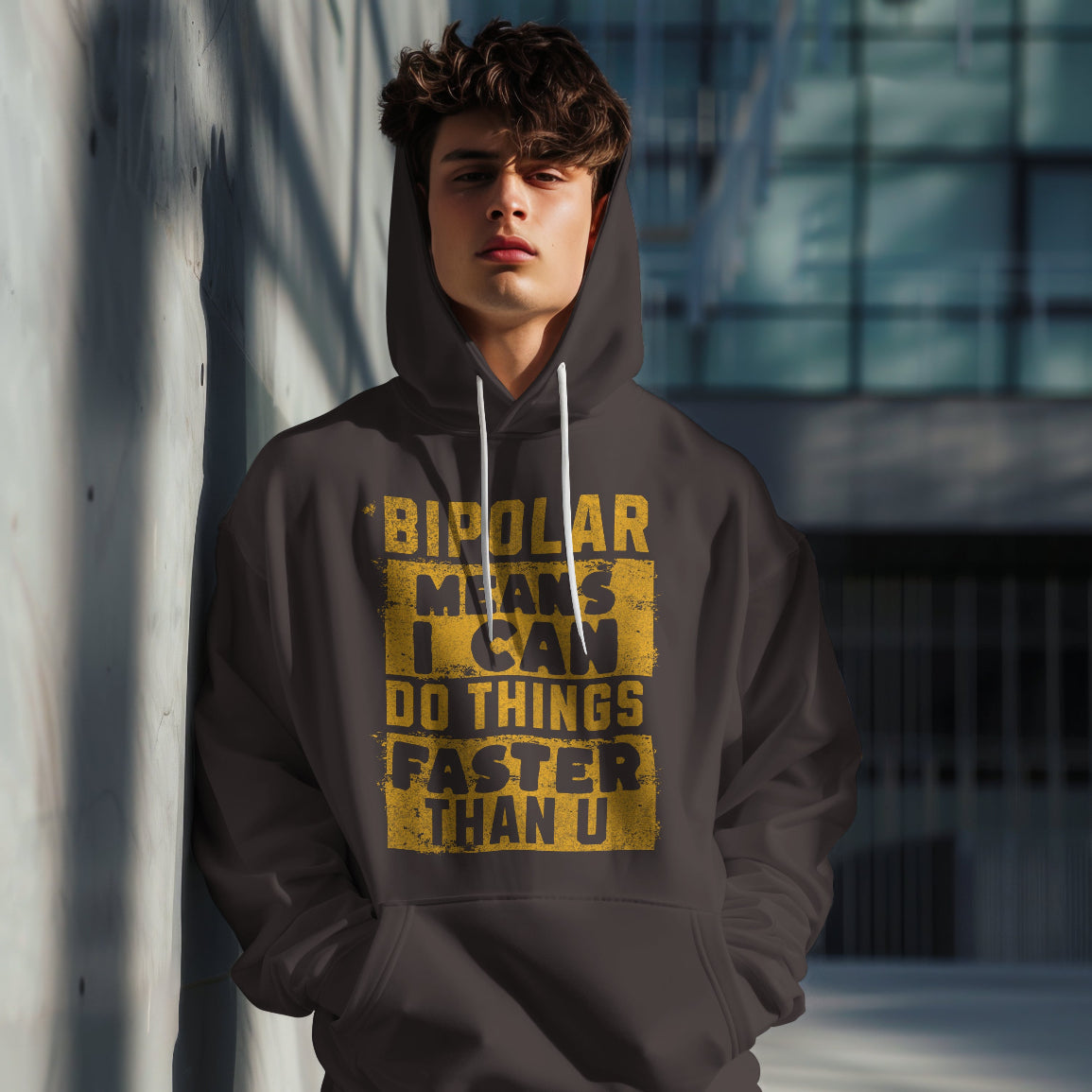 Person wearing a hoodie with text that reads Bipolar Means I can Do Things Faster Than u standing against a wall.