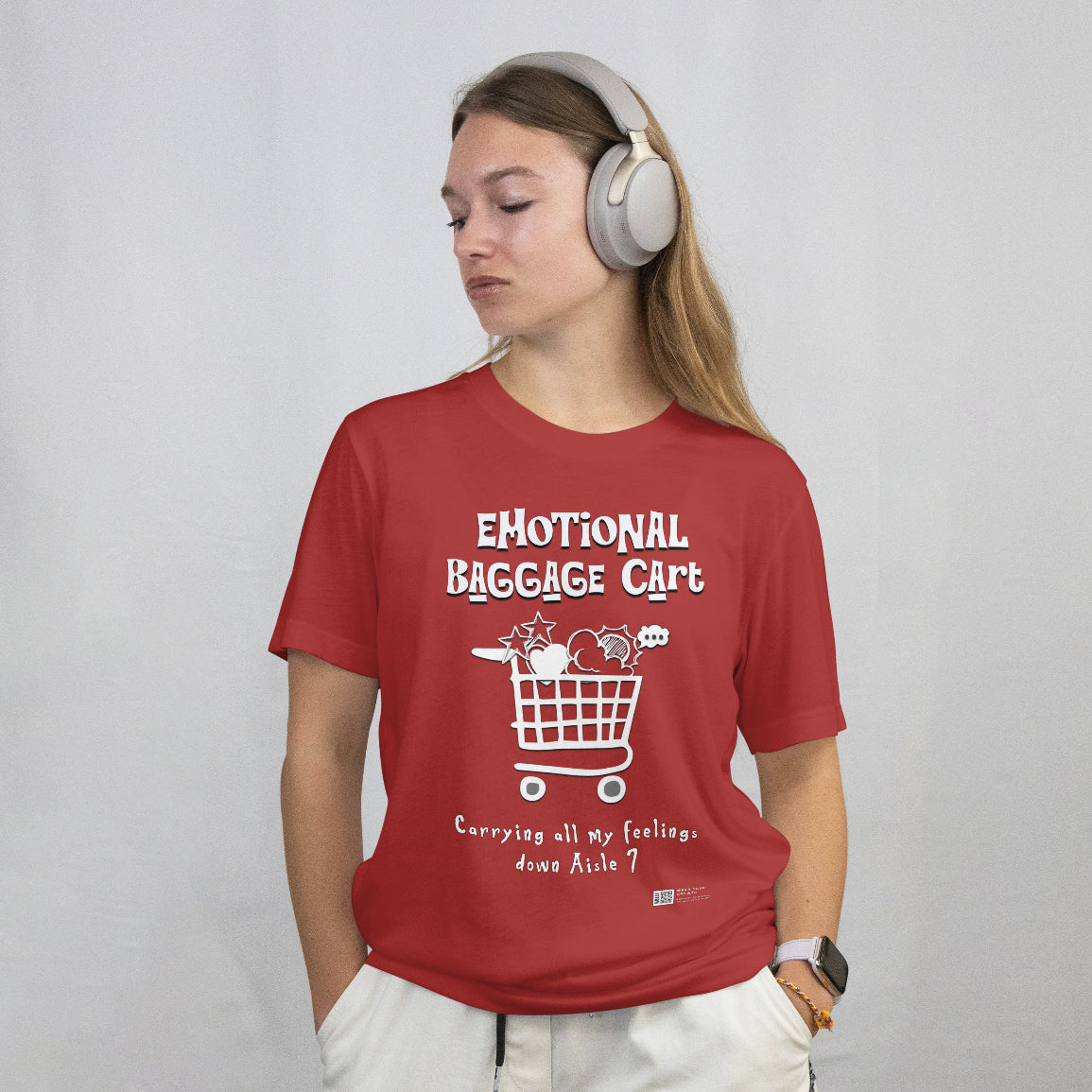 Young woman wearing a red t-shirt with a graphic and text that reads emotional baggage cart, standing against a plain background