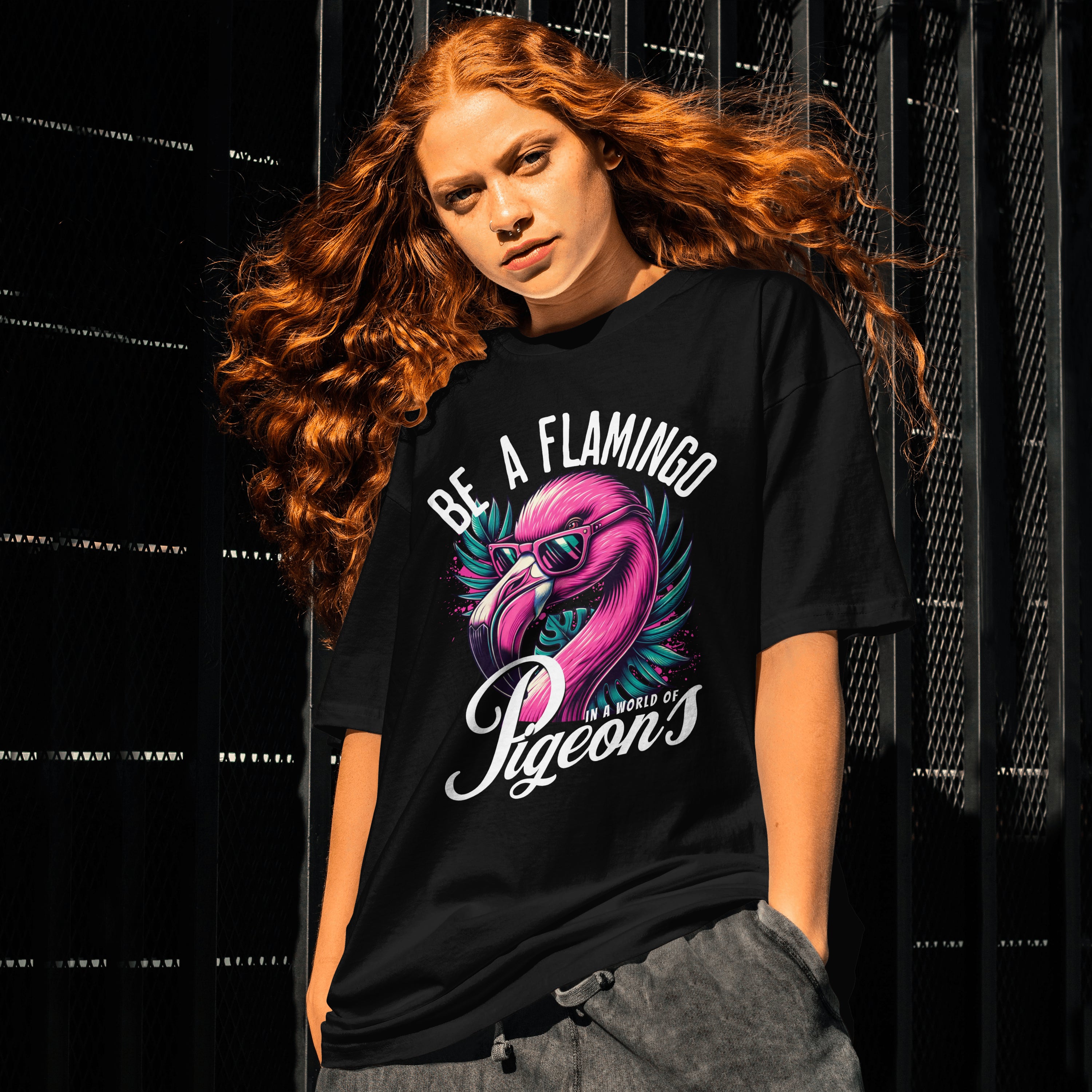Person wearing a black unisex t-shirt with a flamingo graphic and text against a dark background