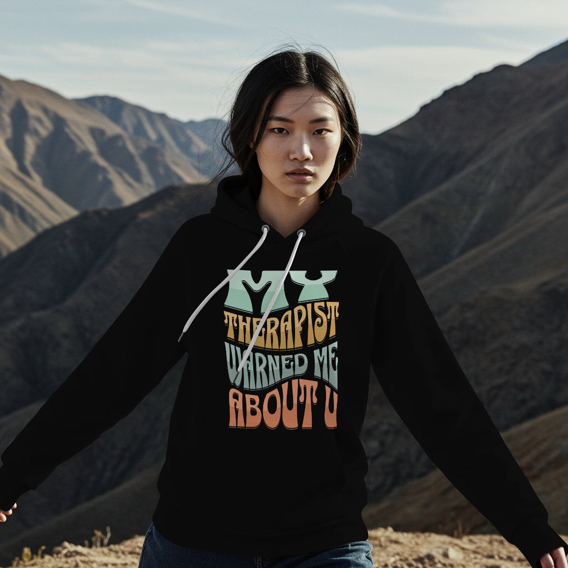 Person wearing a hoodie with text in front of mountainous landscape