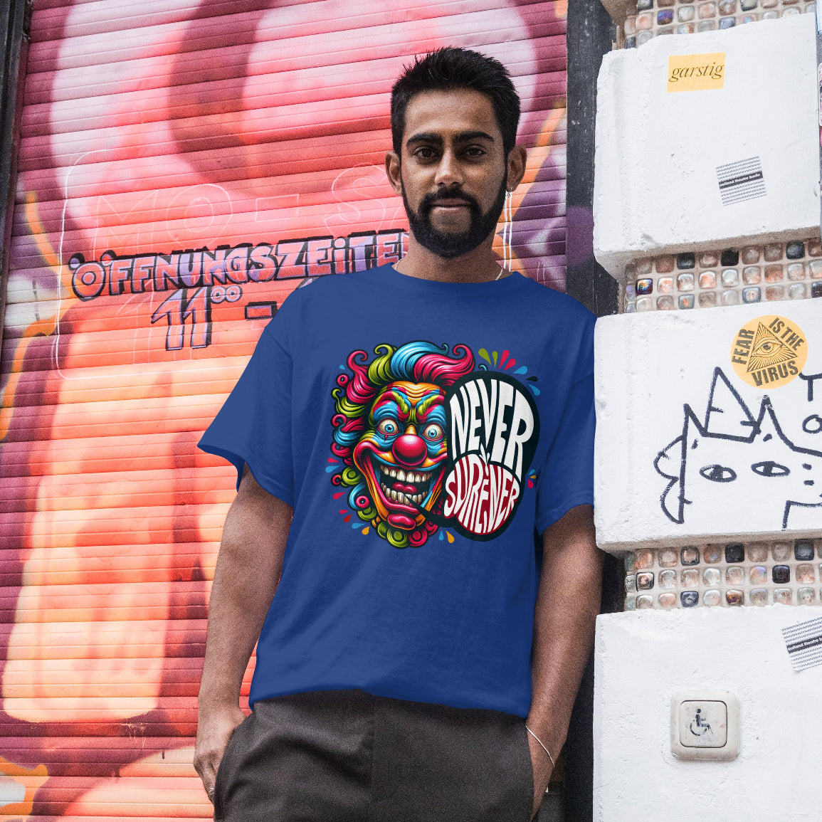 Man wearing a blue t-shirt with a colorful design and text, standing in front of a graffiti-covered wall.