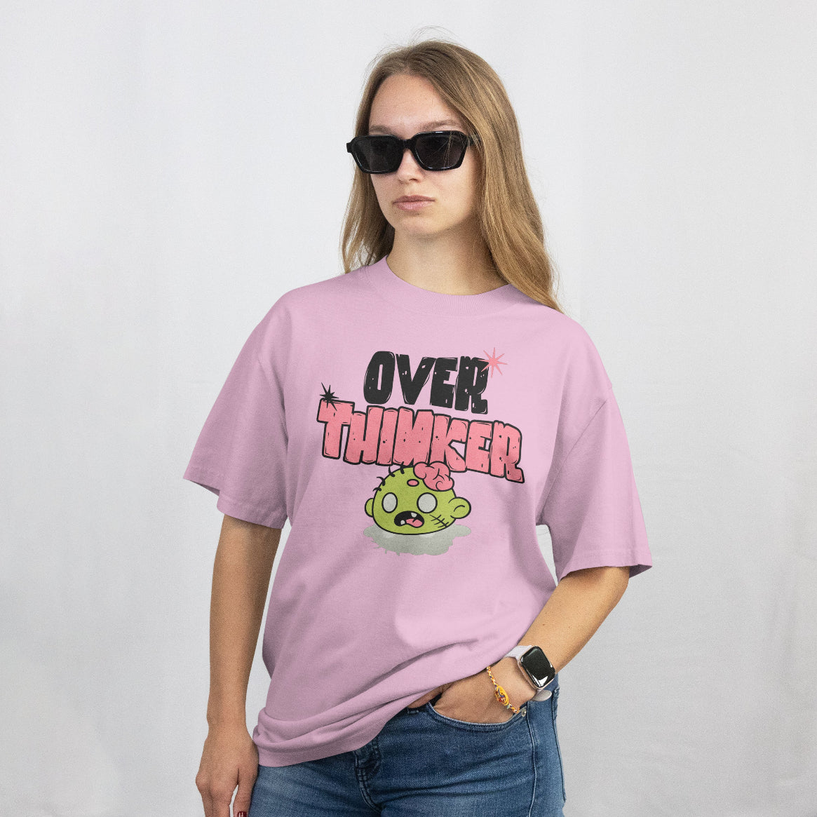 Person wearing a pink t-shirt with 'OVER THINKER' text and cartoon character on a plain background