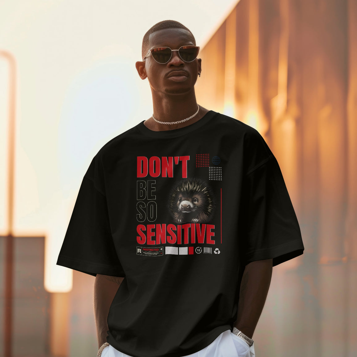 Man wearing a black t-shirt with a graphic design and text, standing against a blurred background.