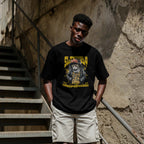 Person wearing a black t-shirt with a graphic design, standing on a staircase.