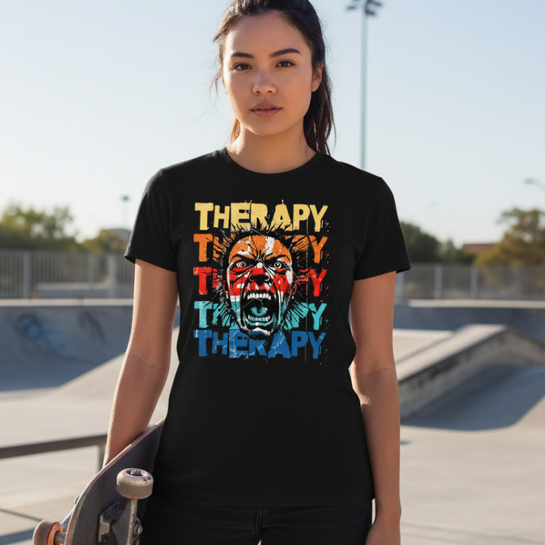 Person wearing a black t-shirt with colorful text and graphic design, holding a skateboard at a skate park.