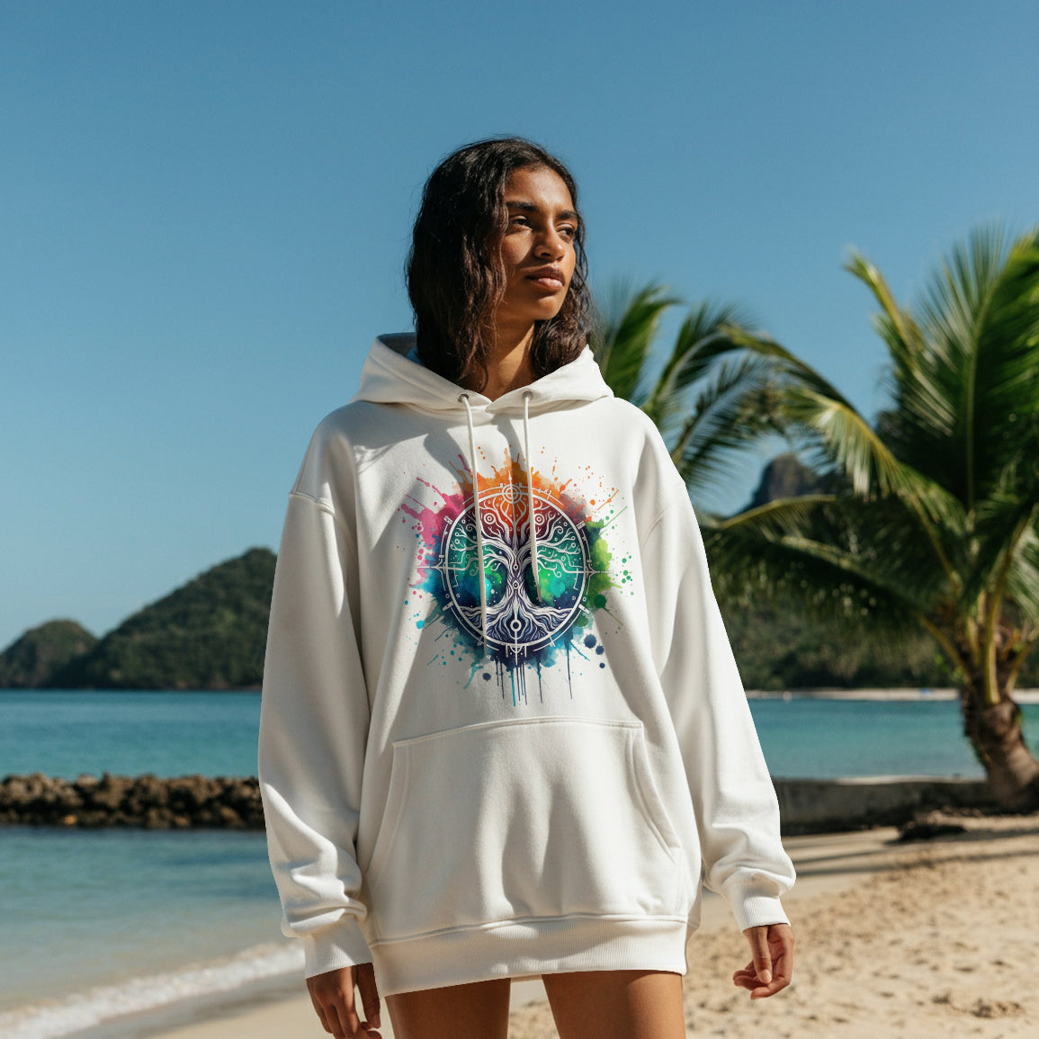 Person wearing a white hoodie with a colorful design on a beach